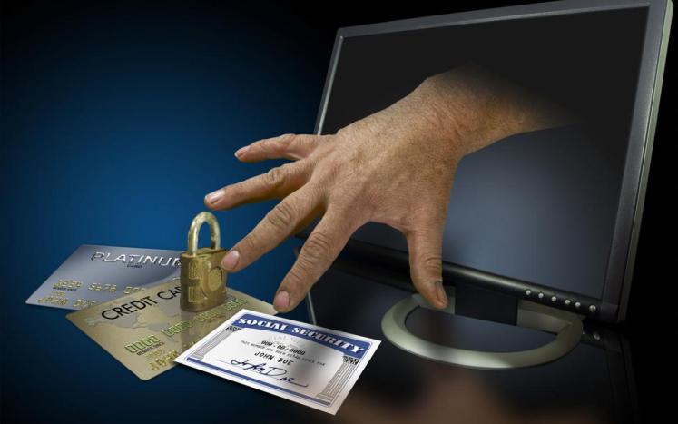 a hand reaching from a computer screen to steal personal information